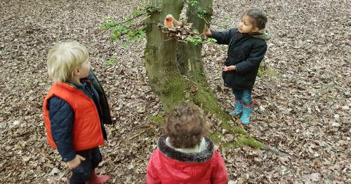young children looking at toy bird in a nest in tree