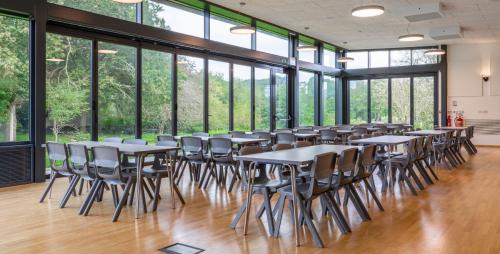 Dining hall with large glass windows and tables in rows with lots of seating