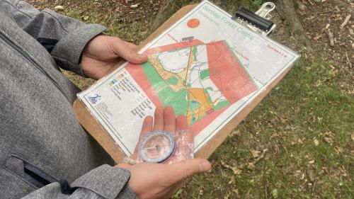 image of someone holding an orienteering map with a compass in one hand